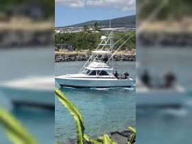 A fishing boat navigates through clear waters, with crew members actively engaged in their fishing activities, showcasing the excitement of a day on the water.