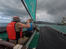 Two individuals enjoy an adventurous sailing experience on a vibrant turquoise sea, showcasing the thrill of exploring the waters.