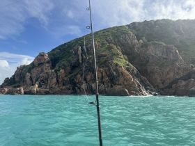 A scenic view of rocky cliffs and turquoise waters, perfect for fishing adventures and exploring coastal beauty.