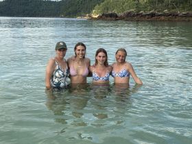 A joyful group of friends enjoys a refreshing swim in crystal-clear waters, perfect for a fun day at the beach.