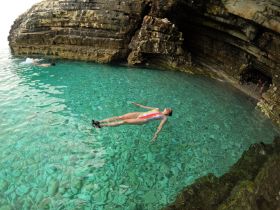 A swimmer enjoys the crystal-clear waters inside a cave, showcasing a perfect spot for adventure and exploration during a boating trip.