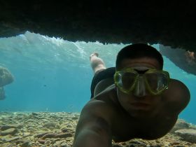 A snorkeler captures an underwater selfie while exploring vibrant marine life and rocky formations — a thrilling experience in the clear blue waters.