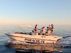 A lively group enjoys a day on the water aboard the 'Parachute' boat, showcasing the joy of on-water activities and camaraderie.