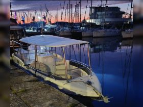 A serene evening view of a boat docked at the marina, reflecting the colorful sunset and surrounding vessels — perfect for a peaceful night on the water.