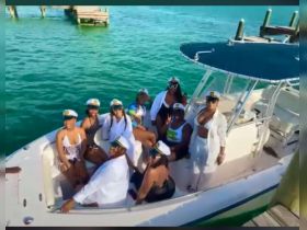 A lively group of friends celebrates on a boat, all wearing matching captain hats, enjoying a fun day on the water.