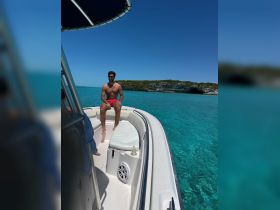 A man relaxes on the deck of a boat under the bright sun, surrounded by stunning turquoise waters — a perfect moment for enjoying the beauty of the ocean.