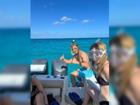 A group enjoys a fun snorkeling adventure on a boat, showcasing the excitement of exploring vibrant underwater life in crystal-clear waters.