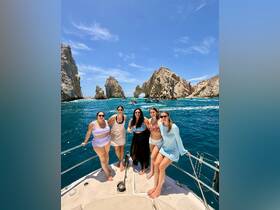 A lively group of friends enjoys a sunny day on a boat near the stunning rock formations of Cabo San Lucas, perfect for memorable celebrations and adventures on the water.
