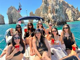 A lively group of friends enjoys a boat party, sipping drinks and celebrating against a stunning coastal backdrop. Perfect for memorable outings and celebrations on the water.