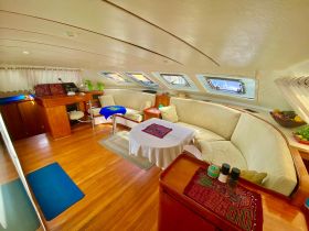 A cozy interior view of a boat's lounge area featuring comfortable seating and natural light streaming through the windows, perfect for relaxation while cruising.