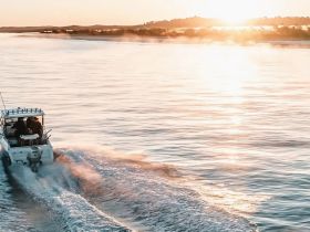 A boat glides through shimmering waters at sunset, creating a picturesque scene perfect for evening cruises and adventures on the water.
