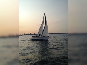 A group enjoys a sailing experience at sunset aboard a yacht, capturing the essence of a perfect evening on the water.