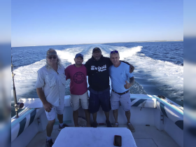 A group of friends poses together on a boat, enjoying a day out on the water — perfect for fishing adventures and camaraderie.