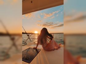 A woman enjoys a serene sunset view from the deck of a yacht, capturing the essence of relaxation and beauty on the water.