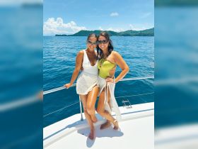 Two friends pose for a cheerful photo on a boat, enjoying a sunny day on the ocean — perfect for memorable outings and celebrations.