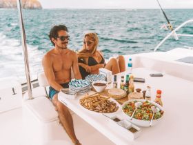 A couple enjoys a delicious spread of food and drinks on the deck of a yacht, perfect for a relaxing day at sea.