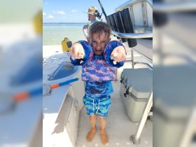 A joyful child poses with excitement on a fishing boat, showcasing the fun of a day on the water. Perfect for family fishing adventures!