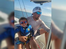 A joyful moment on the water as a father and son enjoy their fishing trip, showcasing the fun and bonding experiences that boating offers.