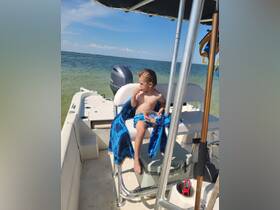 A young child enjoys a snack on a boat, soaking up the sun and the beautiful ocean view — a perfect moment of fun on the water.