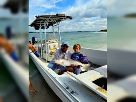 A father and son proudly display their catch of the day while enjoying a fishing trip on a boat, creating lasting memories together on the water.