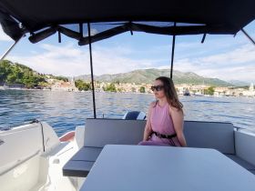 A woman relaxes in the cabin of a boat, enjoying the scenic views of the coastline — perfect for leisurely outings on the water.