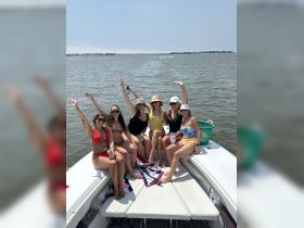 A lively group of friends celebrates on a boat, enjoying drinks and summer vibes — perfect for a fun day on the water.
