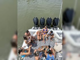 A lively group enjoys drinks and conversation on the deck of a boat under the sun, perfect for summer gatherings and celebrations on the water.