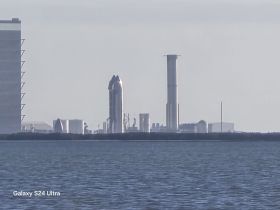An unclear image featuring structures near the water, lacking identifiable subjects or clarity.