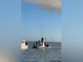 A group of people aboard a boat enjoys an exciting moment on the water, with a rocket launch in the background, making for a thrilling experience.