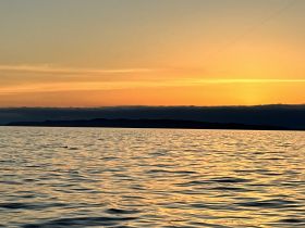 A stunning sunset over tranquil waters, with an island silhouette in the distance — a perfect backdrop for evening boat trips and scenic cruises.