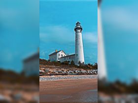 A scenic view of a lighthouse on the shore, surrounded by natural landscapes, showcasing coastal architecture.