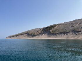 A stunning view of a sandy coastline with gentle waves lapping at the shore, perfect for showcasing the natural beauty of the area.