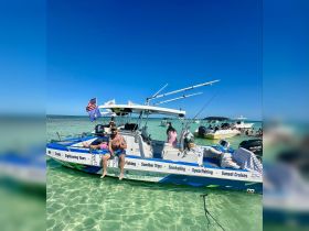 Guests enjoy a lively sandbar stop aboard a charter boat, perfect for fishing and snorkeling adventures in crystal-clear waters.