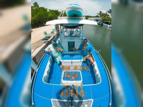 Two anglers proudly display their catch of lobsters on the deck of a boat, celebrating a successful fishing trip in sunny waters.