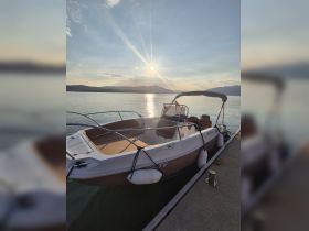 A serene view of a boat docked at sunset, reflecting the warm colors of the sky on calm waters — perfect for a peaceful evening on the water.