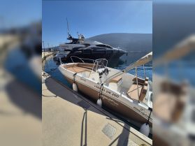 A sleek speedboat named 'Speedy' docked at a marina, showcasing its stylish design against a backdrop of luxury yachts and clear blue skies.