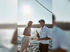A couple enjoys a delightful moment on a boat, sharing snacks and drinks under the sun — perfect for romantic sunset cruises or special celebrations.