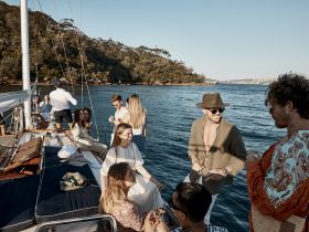 A lively group of friends enjoys drinks and laughter aboard a yacht, capturing the essence of a perfect day on the water.