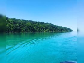 A serene view of turquoise waters and lush green coastline, perfect for showcasing the beauty of nature during a boating trip.
