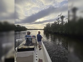 Two friends enjoy a peaceful fishing trip at sunset, surrounded by lush mangroves — a perfect escape into nature on the water.