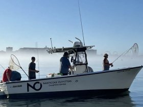 A group of anglers enjoys a fishing trip aboard a charter boat, surrounded by a misty backdrop — perfect for a day of adventure on the water.
