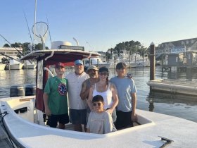 A cheerful family poses together on a boat at the dock, capturing a memorable moment before their fishing adventure.