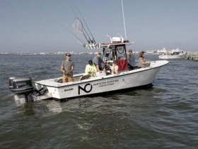 A group enjoys a fishing charter aboard a boat, showcasing the excitement of on-water activities and camaraderie in a beautiful setting.
