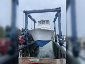 A fishing boat is being lifted out of the water at a dock, showcasing its sleek design and readiness for maintenance or transport.