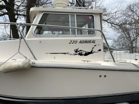 A detailed view of the side of the '220 Admiral' boat, showcasing its sleek design and distinctive graphics, perfect for marine enthusiasts.
