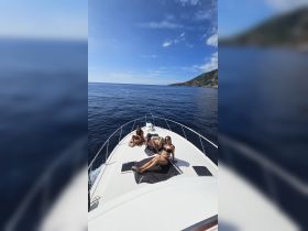 A group of friends relaxes on the bow of a boat, enjoying the sun and ocean views — perfect for a day of fun on the water.