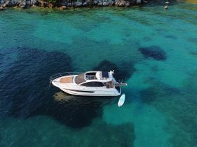 A stunning aerial view of a sleek yacht cruising through crystal-clear turquoise waters, perfect for exploring coastal destinations.