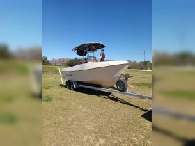 A speedboat is seen on a trailer with a person standing beside it, showcasing its sleek design and readiness for the water.