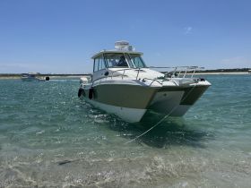 A sleek catamaran is docked in clear waters, showcasing its elegant design against a sunny backdrop — perfect for day trips and water adventures.
