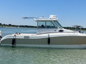 A sleek speedboat is anchored in clear waters, showcasing its modern design and fishing gear, perfect for a day on the water.